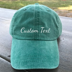 May include: A green baseball cap with white embroidered text that says "Custom Text".