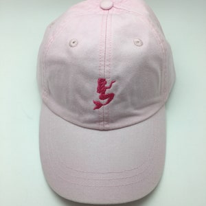 Puede incluir: Una gorra de b&eacute;isbol rosa con un dise&ntilde;o de sirena bordado en rosa.