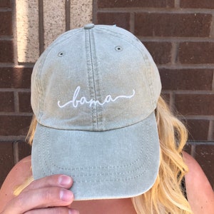 May include: A green baseball cap with the word "bama" embroidered in white on the front.