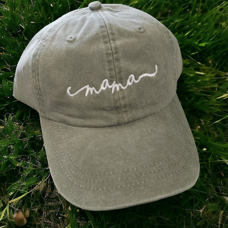 May include: A green baseball cap with white embroidery that says "mama".