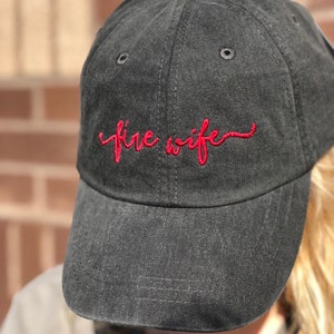 May include: Black baseball cap with a red embroidered cursive script that says "fire wife".