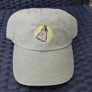 May include: A green baseball cap with an embroidered image of a wolf howling at the moon.