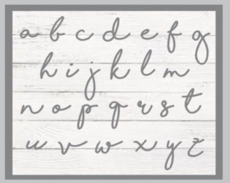 May include: A white wood background with the alphabet written in cursive in gray paint.