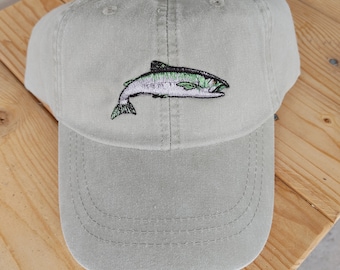 May include: A light green baseball cap with an embroidered image of a salmon fish.