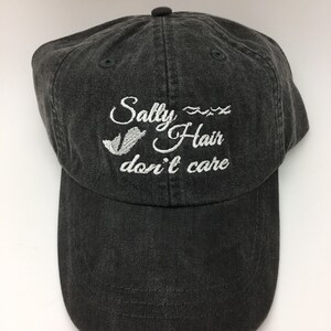 May include: A black baseball cap with white embroidery that reads "Salty Hair don't care" with a wavy line and a small seagull graphic.