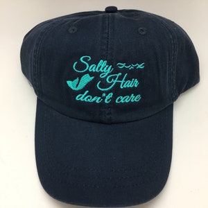 May include: A navy blue baseball cap with the text "Salty Hair don't care" embroidered in turquoise.
