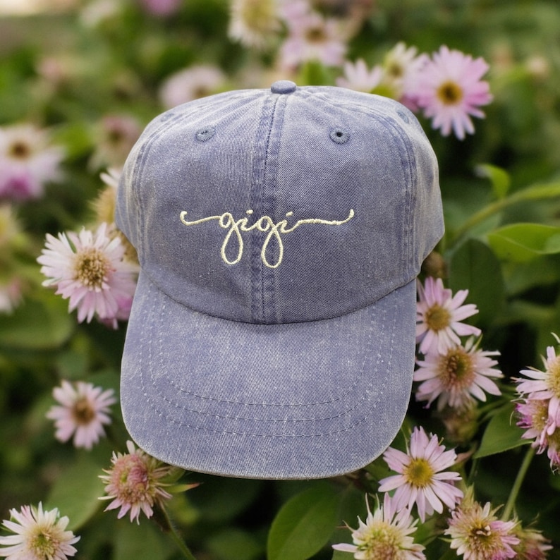 May include: A blue denim baseball cap with the word "gigi" embroidered in white on the front.