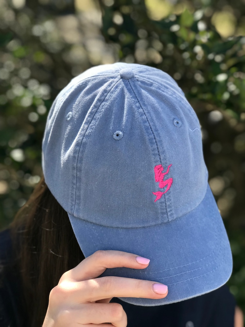 Puede incluir: Una gorra de b&eacute;isbol de mezclilla azul con un dise&ntilde;o de sirena bordado en rosa.