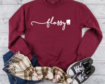 May include: A maroon long-sleeved sweatshirt with the text "flossy" and a white tooth graphic.