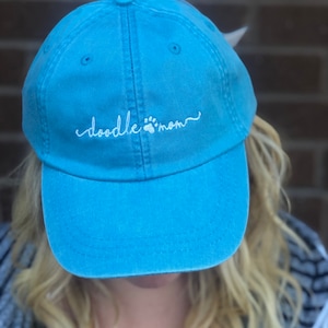May include: A blue denim baseball cap with white embroidery that reads "doodle mom" with a paw print symbol.
