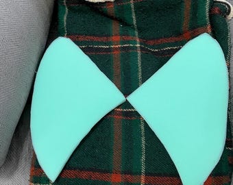 May include: Two light blue foam shapes, possibly for a craft project, are laid out on a green, red and black plaid fabric.