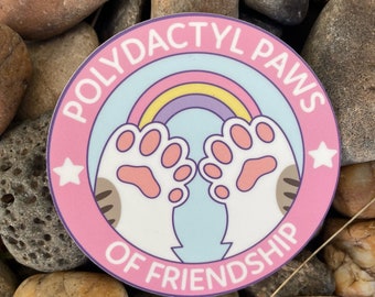 May include: Pink and blue sticker with a rainbow, two white paws with pink paw pads, and the text "Polydactyl Paws of Friendship" in a white circle.
