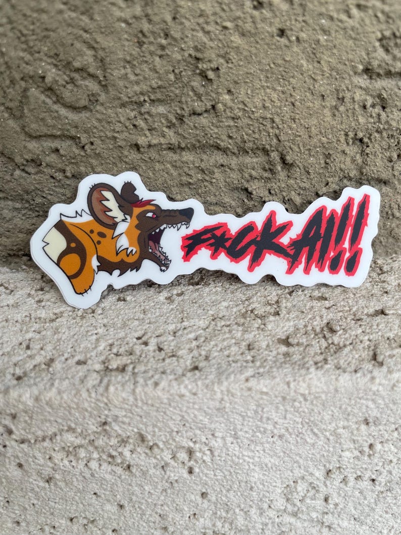 May include: A white sticker with a cartoon African wild dog in brown, tan, and black. The sticker has the red text "F*CK A!!". The dog is baring its teeth, and the sticker is on a textured surface.