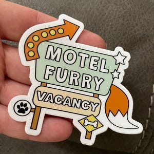 sticker cut into the shape of a motel sign with arrow, stars and tail attached. text reads motel furry — vacancy with a paw print and bone symbol underneath.