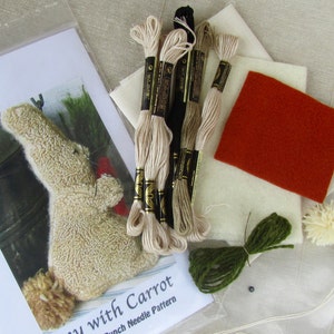 May include: A craft kit with a "Doodle Dog Designs" pattern for a bunny with a carrot. The kit includes embroidery floss in various colors, felt squares, and pom-poms. The bunny pattern is visible on the packaging.
