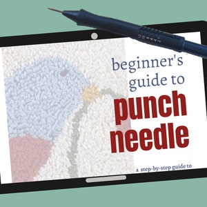 May include: A black tablet displays a "beginner's guide to punch needle" with a step-by-step guide. A blue punch needle tool rests on the tablet. The screen shows a close-up of a textured, colorful fabric.