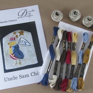 May include: A punch needle pattern kit featuring an Uncle Sam Chicken design. The kit includes a pattern, embroidery floss in various colors, and several spools of thread. The design is patriotic with red, white, and blue colors.