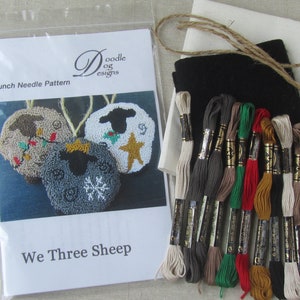 May include: A punch needle pattern kit featuring three sheep ornaments with holiday designs. The kit includes a pattern, embroidery floss in various colors, black felt, and other materials. The pattern is titled "We Three Sheep".