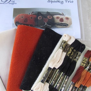 May include: A craft kit with the title "Spooky Trio" includes felt in orange, black, and white, along with embroidery floss in various colors. The kit also contains a pattern for making Halloween-themed decorations.