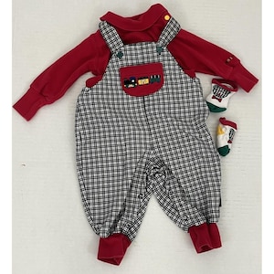 May include: A red long-sleeved shirt and a black and white check overall with a train applique. The outfit includes two pairs of socks with bow tie and train designs. The baby clothing set is designed for infants.