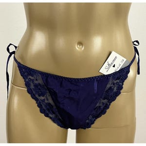 May include: Navy blue silk underwear with delicate lace trim along the edges. The underwear has tie sides and a small tag that reads "Silkscreen Washable Silk."
