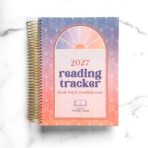 May include: A spiral-bound 2027 reading tracker book log and reading stats planner with a gold wire coil. The cover features a gradient from purple to orange with an art deco fan pattern and a central arch graphic containing the text 2027 reading tracker.
