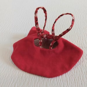 May include: Red fabric doll dress with white and black patterned straps.