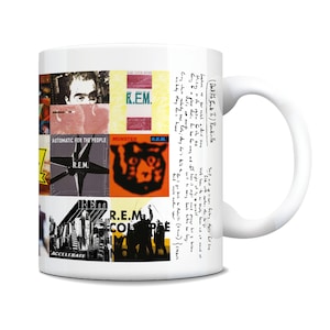 May include: White ceramic mug with a collage of album covers from the band R.E.M. The album covers include "Automatic for the People", "Monster", "Accelerate", and "Collapse into Now".