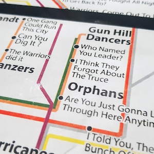 May include: A subway map with lines and stops labeled with names and phrases. The map is printed on white paper with red, orange, yellow, green, blue, and purple lines. The names of the stops include "Van Cortlandt Rangers", "Gun Hill Dancers", "Orphans", "Panzers", "The Warriors", "Can You Dig It?", "One Gang Could Run This City", "Who Named You Leader?", "I Think They Forgot About The Truce", "Are You Just Gonna Let An Army Through Here Anytime They Feel", "I Told You, They're Bunch", "Turnbull", "Moore", and "Looking Warriors".