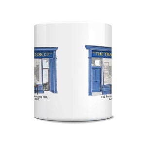 May include: White ceramic mug featuring a detailed illustration of a bookstore facade in blue and white. The mug has the text "THE TRAVEL BOOK CO" and "142 Portobello Rd, London" printed on it. A charming gift for book lovers.