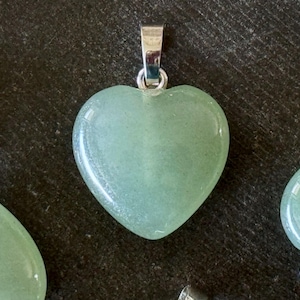 May include: A light green heart-shaped pendant made of polished stone with a silver bail.