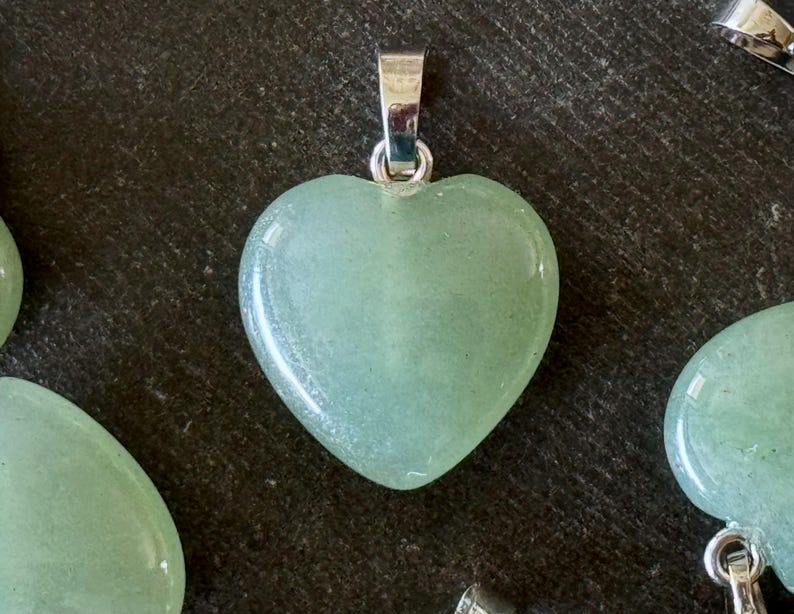 May include: A light green heart-shaped pendant made of polished stone with a silver bail.