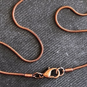 Puede incluir: Un collar de cadena de serpiente de cobre con cierre de mosquetón.