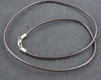 Peut inclure: Un collier en cordon de cuir marron avec des fermoirs argentés.
