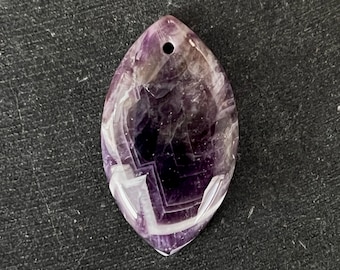 May include: A purple and white amethyst pendant with a hole at the top for a chain. The pendant is shaped like a teardrop and has a smooth, polished surface.