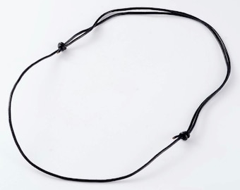 Könnte beinhalten: Eine schwarze Lederkordelkette mit einem einfachen Knoten an jedem Ende.