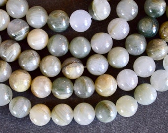 May include: A strand of round, white and gray gemstone beads with a subtle shimmer. The beads have a natural, striated pattern.