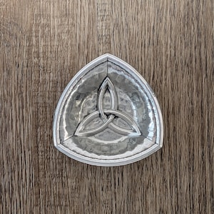 May include: A silver triangular dish with a Celtic knot design.