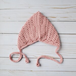 Pu&ograve; includere: Un berretto per neonato in crochet rosa con lacci. Il berretto &egrave; realizzato con un semplice motivo a punto e ha una forma a punta.