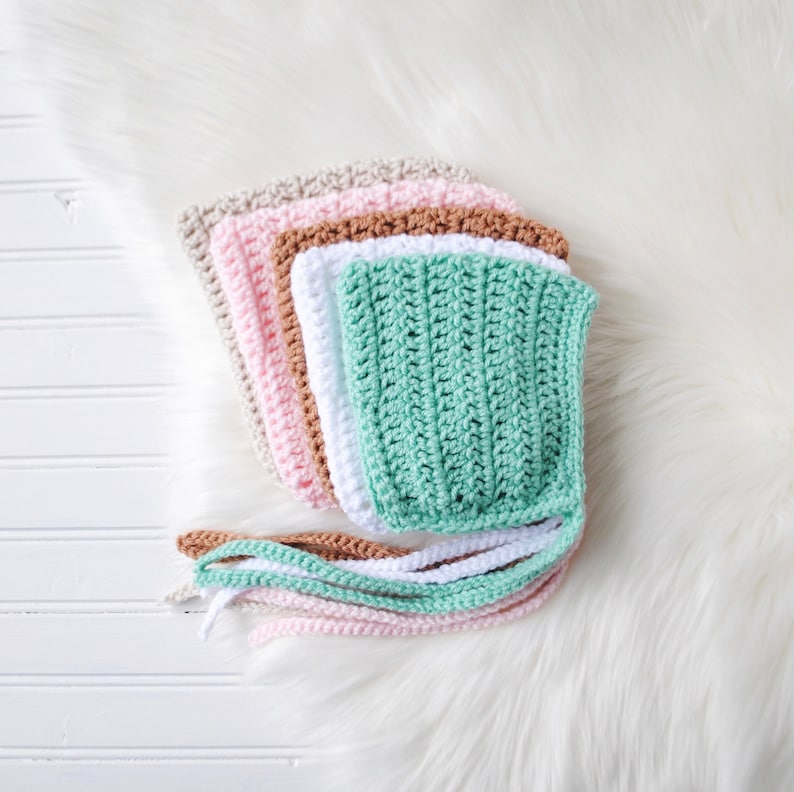 Pu&ograve; includere: Cinque berretti per neonati all'uncinetto in diversi colori: verde, bianco, marrone, rosa e beige. I berretti hanno lunghi lacci.