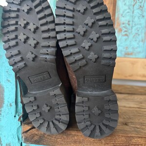 Puede incluir: Un par de botas de color marr&oacute;n oscuro con suelas de goma negra gruesas y tacos profundos para mayor tracci&oacute;n. Las suelas tienen un tac&oacute;n prominente y un patr&oacute;n texturizado, con la marca SHABBIES grabada en un recuadro rectangular.