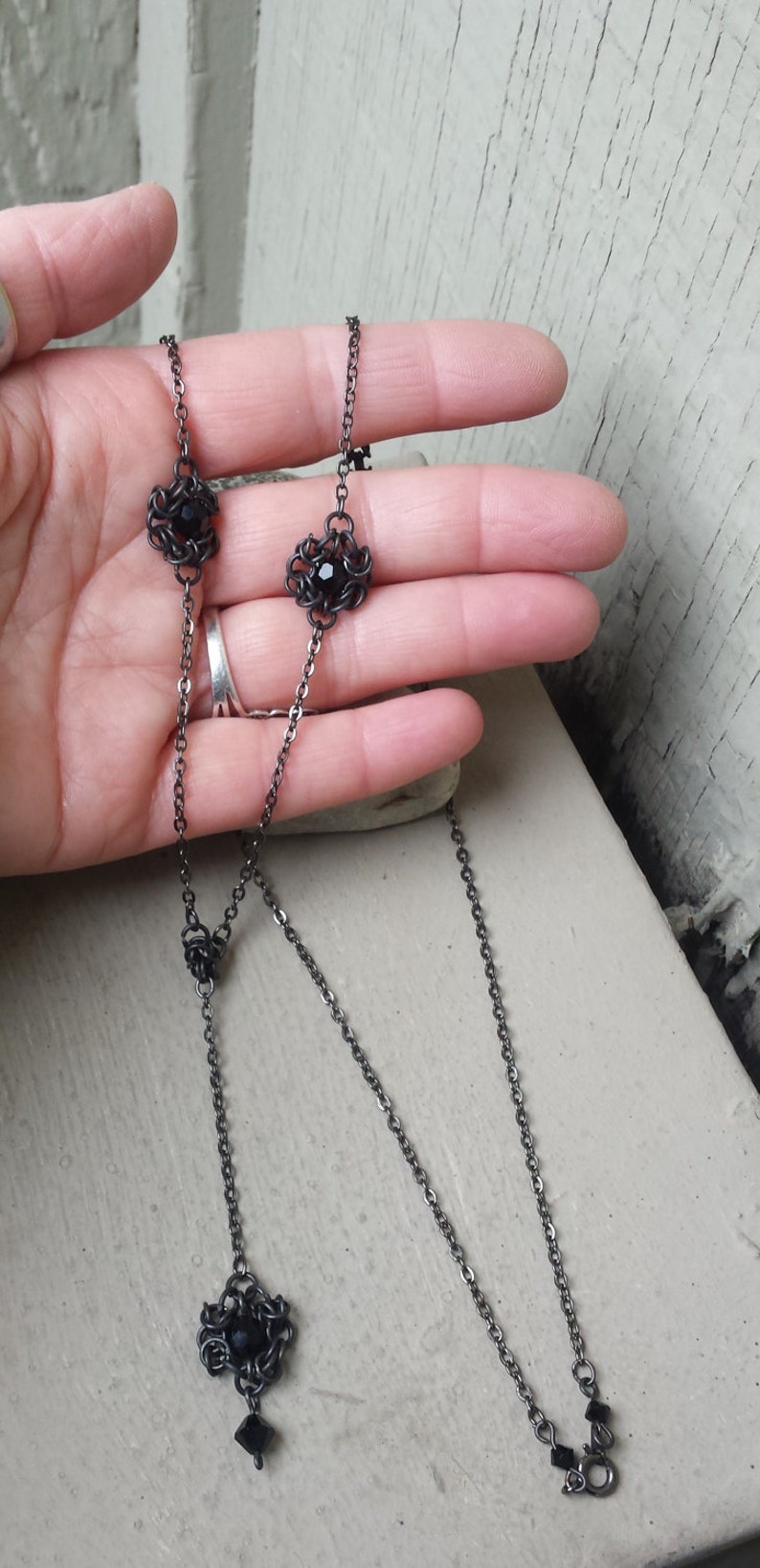 May include: A black chain necklace with three black crystal accents. The necklace is layered and has a lobster clasp closure.
