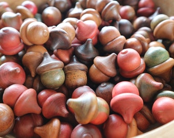 May include: A bowl filled with wooden acorn-shaped toys painted in various shades of brown, red, and green.