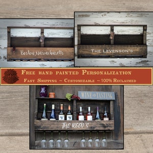 May include: A dark brown wooden wall-mounted wine rack featuring a shelf for bottles and a lower rack for hanging wine glasses. The front panel displays white text including Boston, Massachusetts, The Levenson's, and The Reed's.