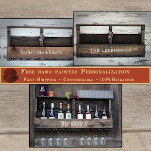 May include: A dark brown wooden wall-mounted wine rack with a shelf for bottles and a rack for hanging wine glasses. The front panel features white text including Boston, Massachusetts, The Levenson's, and The Reed's in different examples.
