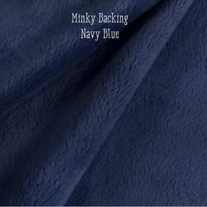 May include: Close-up of navy blue minky fabric, displaying a soft, textured surface. The image includes the text "Minky Backing Navy Blue" in white lettering.