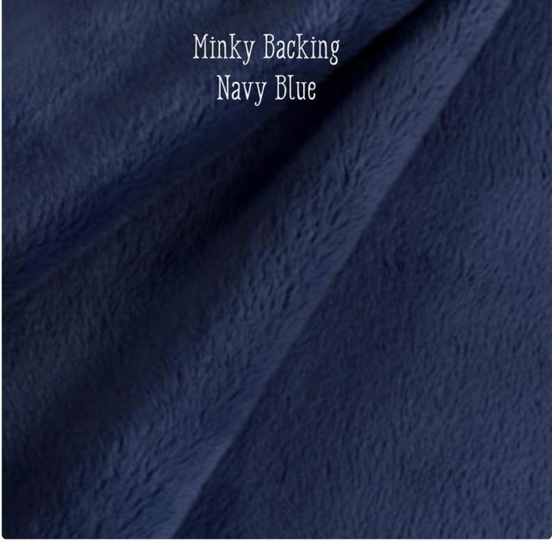 May include: Close-up of navy blue minky fabric, displaying a soft, textured surface. The image includes the text "Minky Backing Navy Blue" in white lettering.