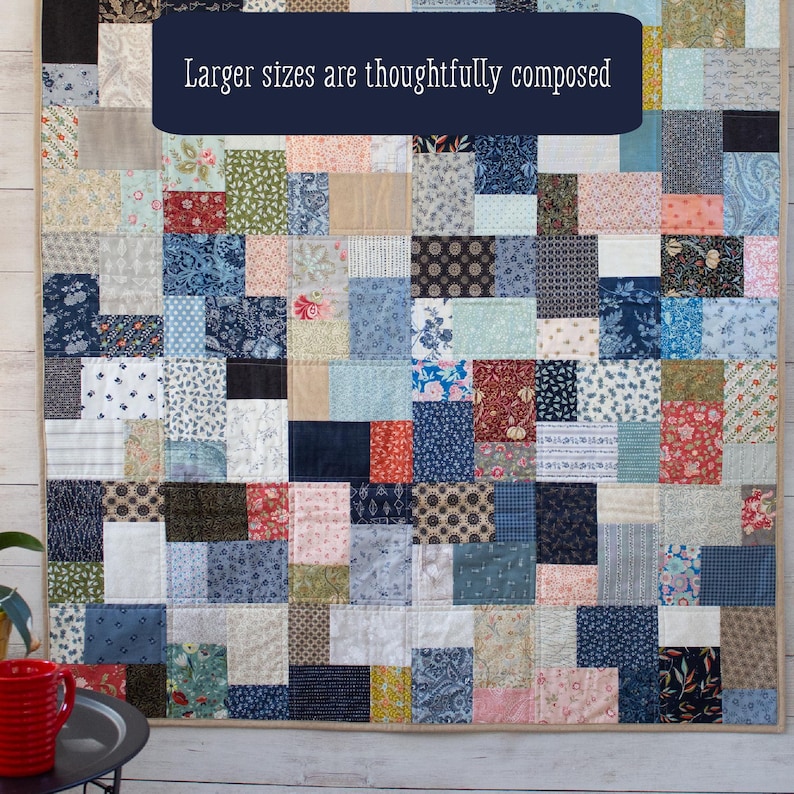 May include: A patchwork quilt featuring a mix of patterned fabric squares in blue, red, cream, and black. The quilt has a beige border and the text "Larger sizes are thoughtfully composed" in a navy blue banner.