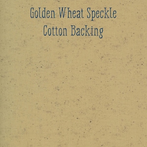 May include: A close-up of a tan fabric with a speckled pattern. The text "Golden Wheat Speckle Cotton Backing" is printed in dark blue across the top of the fabric. The fabric has a woven texture.
