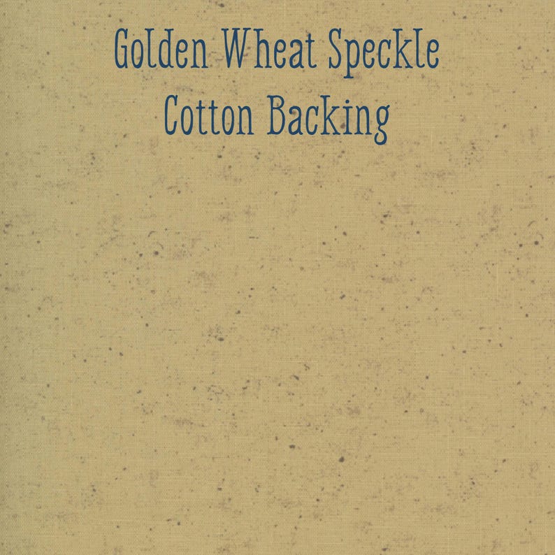 May include: A close-up of a tan fabric with a speckled pattern. The text "Golden Wheat Speckle Cotton Backing" is printed in dark blue across the top of the fabric. The fabric has a woven texture.